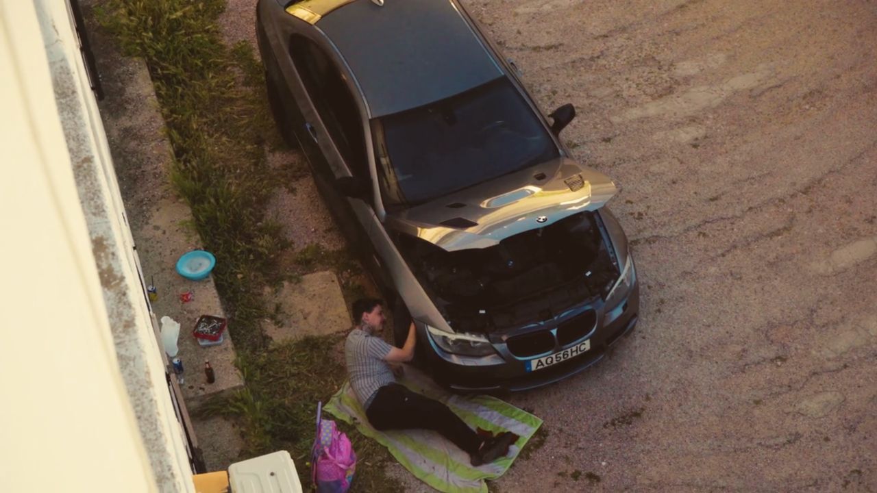 Man lying beside his car in Tudo Bem